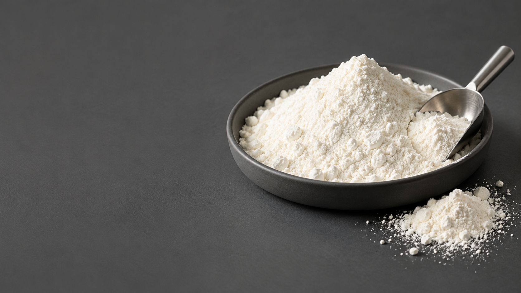 Ingrediente en polvo blanco en un recipiente gris grafito con una pala de acero inoxidable